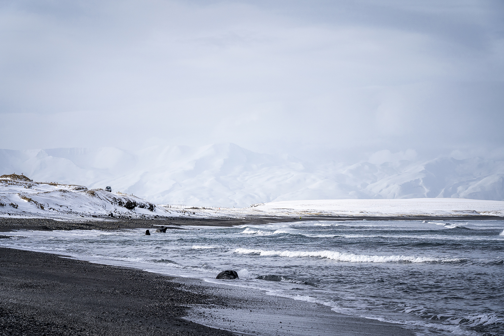 plage de sable noir montagnes mer neige