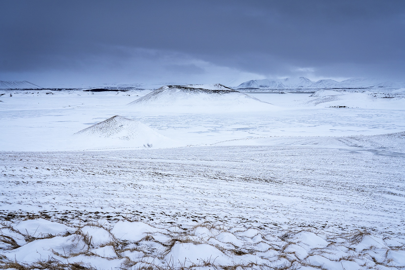 lac gelé volcans Mývatn Skútustaðagígar Islande du Nord nuages noirs neige