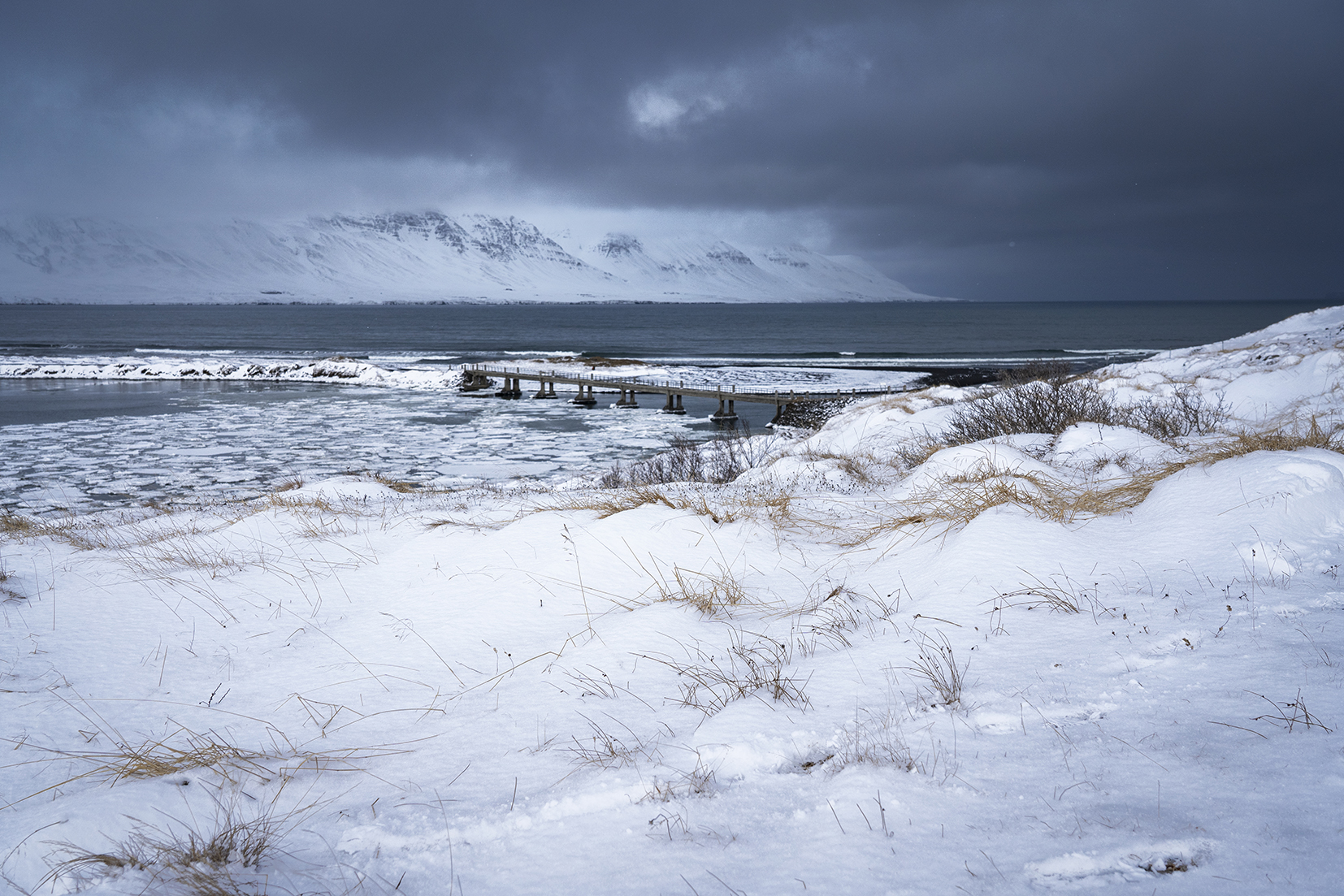 Skagafjördur Islande du Nord ponton montagnes mer neige nuages noirs