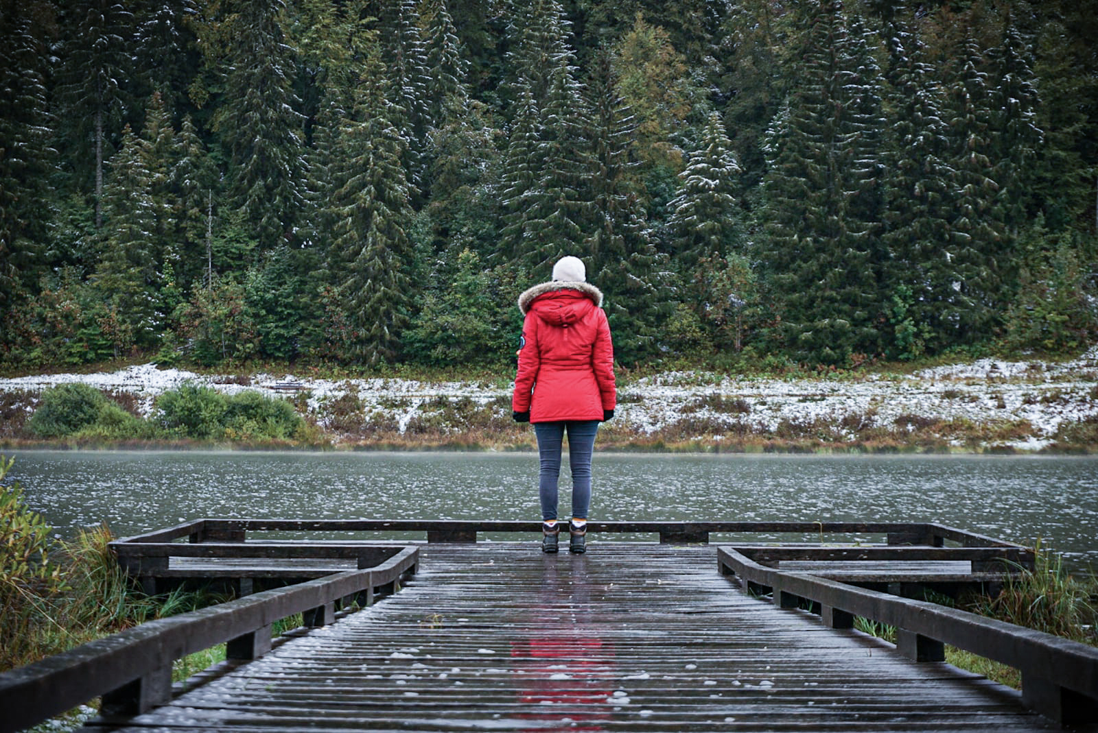 Jura lac Lamoura ponton bois sapins neige personne manteau rouge